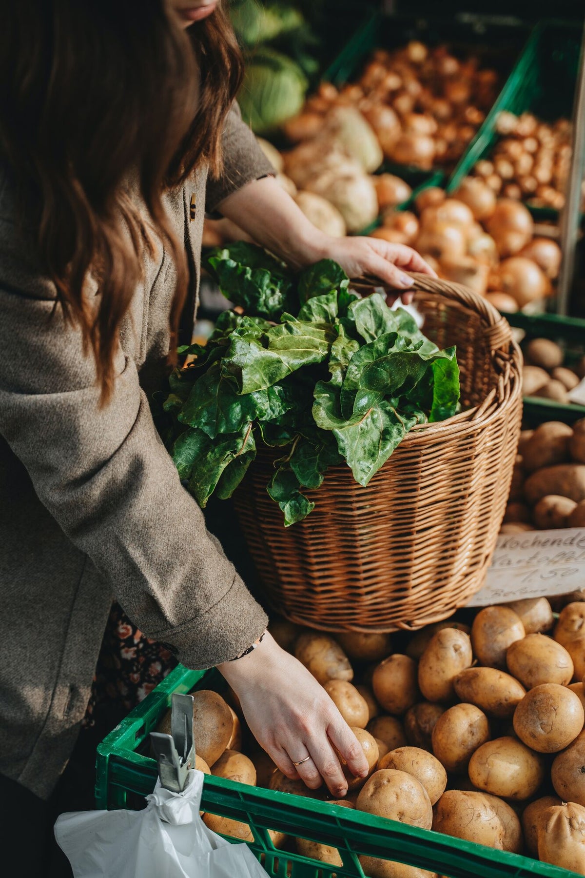 Person füllt ihren Korb am Markt mit Gemüse