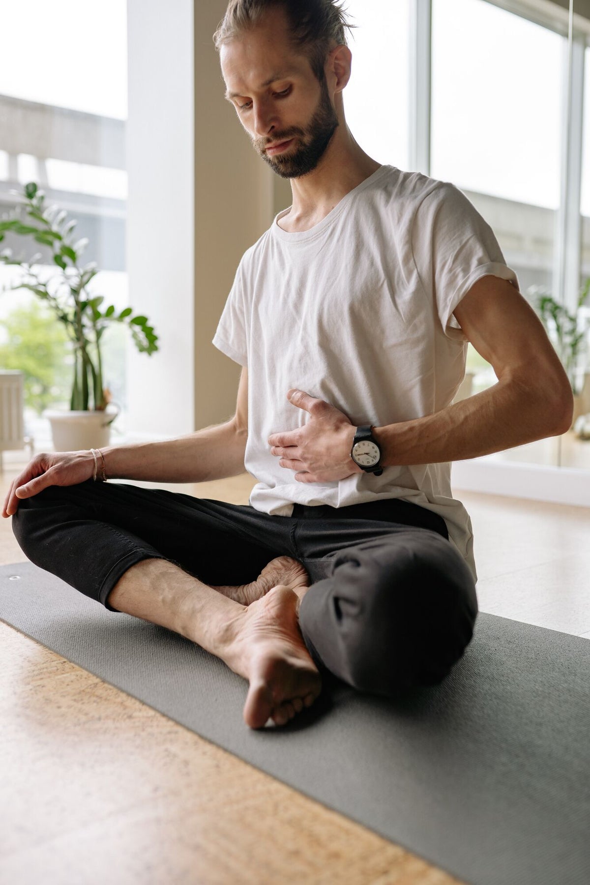 Mann auf Yogamatte haelt sich den Bauch