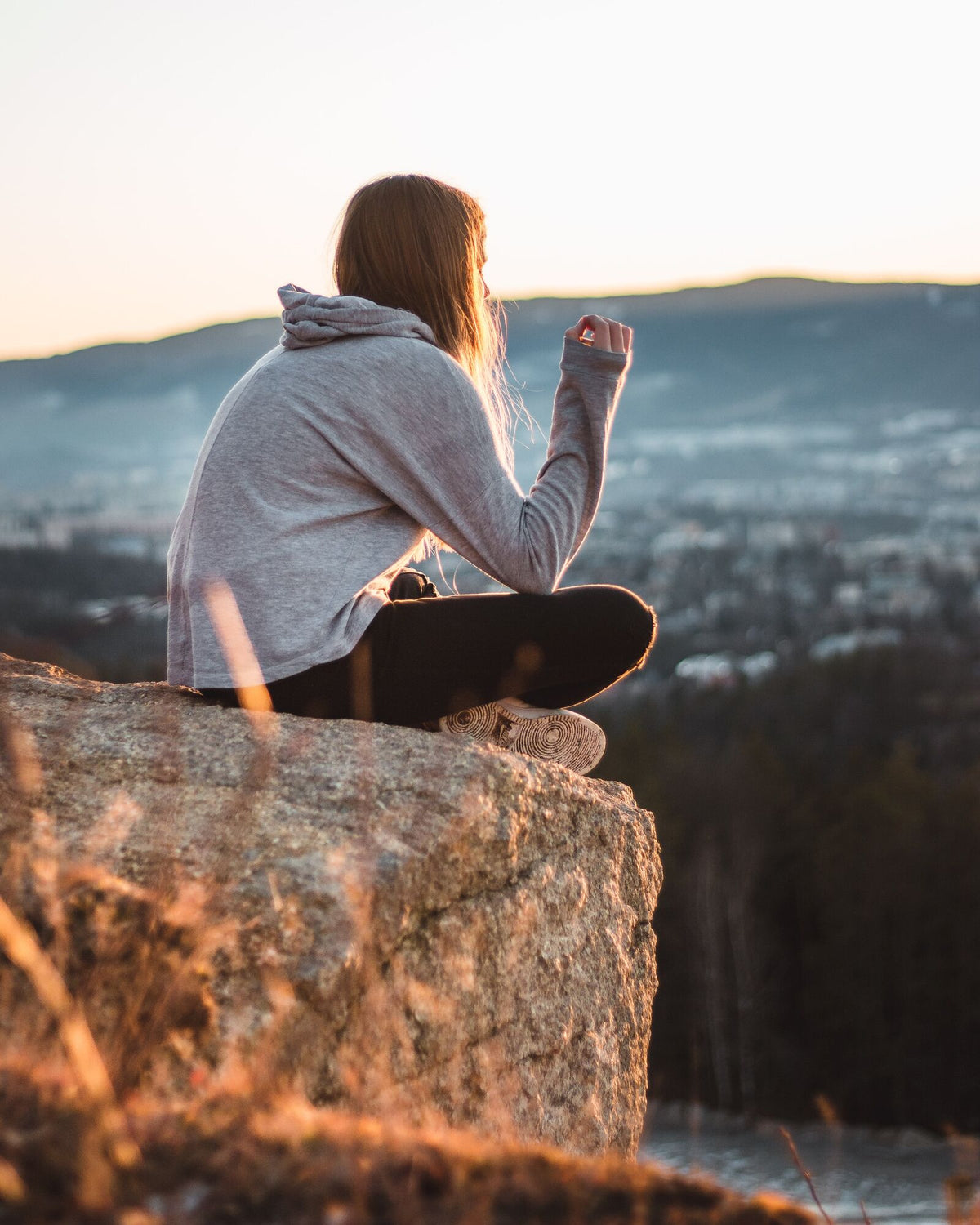 Frau sitzt auf einem Stein im Sonnenuntergang