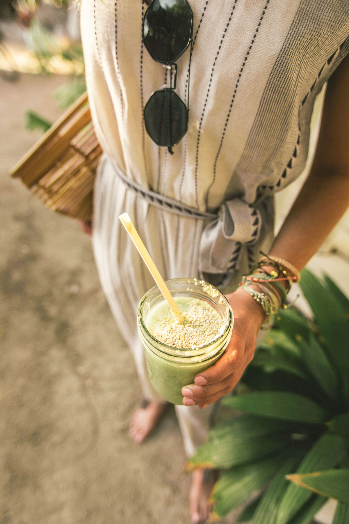 Frau am stran haelt gesunden smoothie in der hand