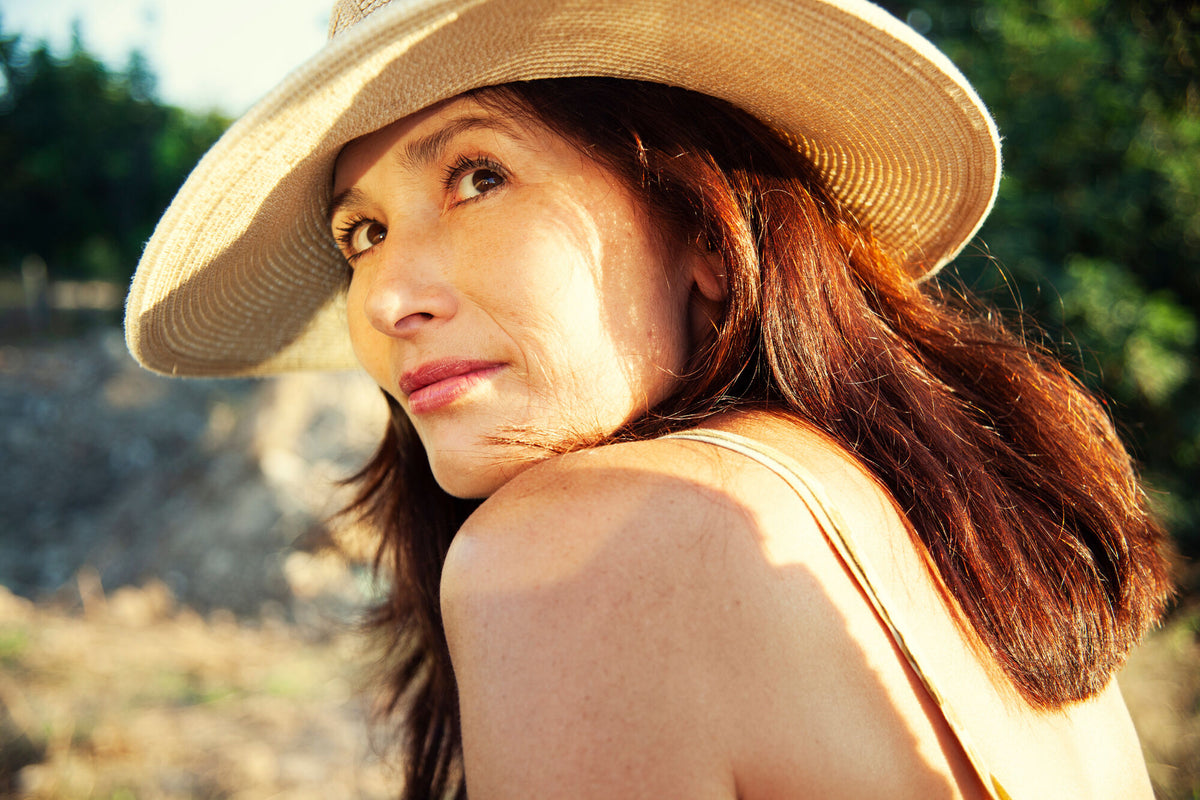 Frau mit Hut schaut in die Sonne