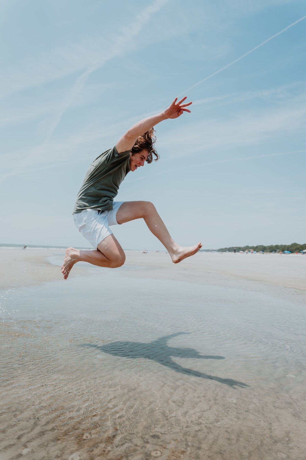 Mann springt energiegeladen am Strand in die Luft